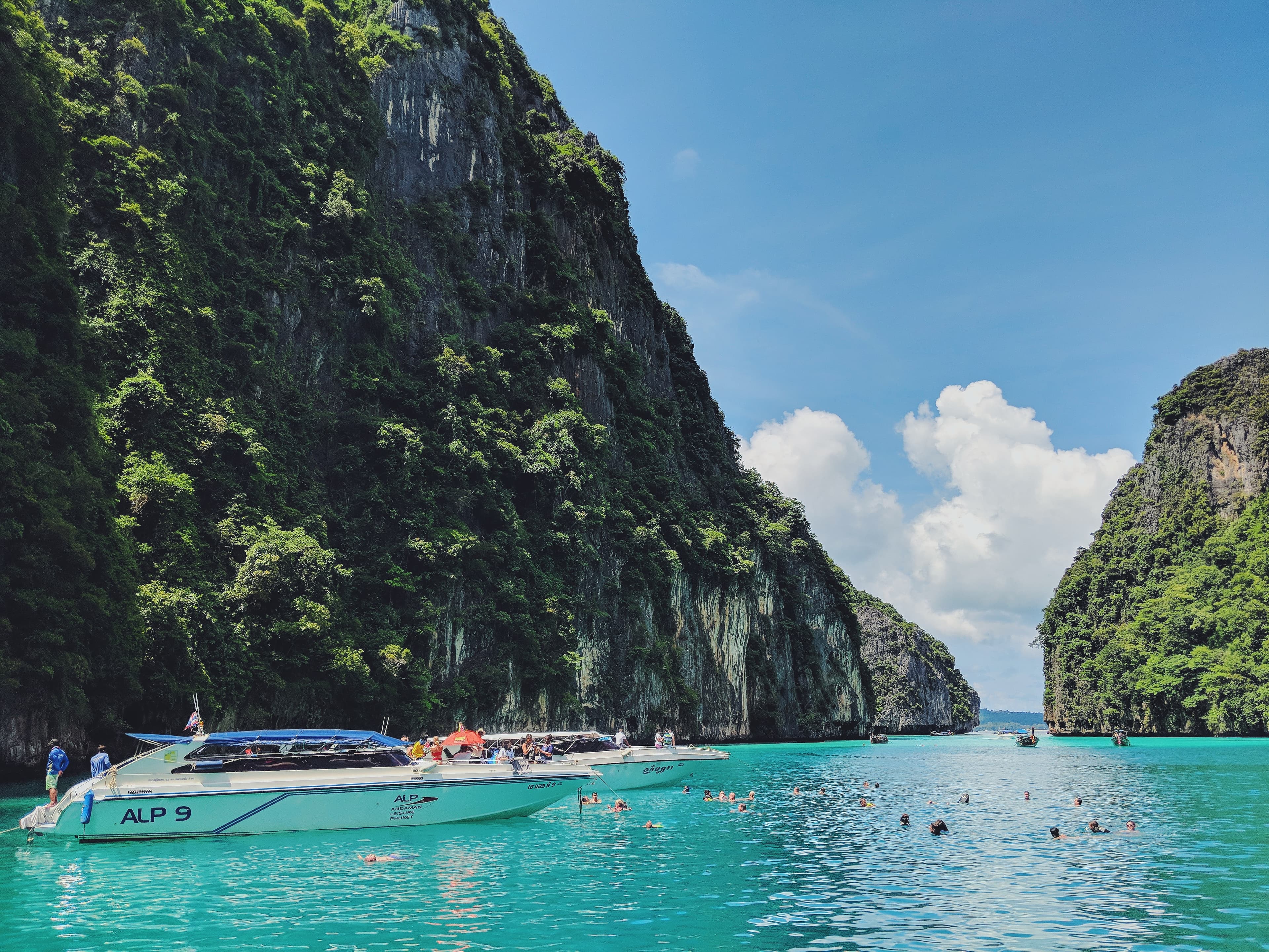 boat in body of water next to tall rocks during daytime