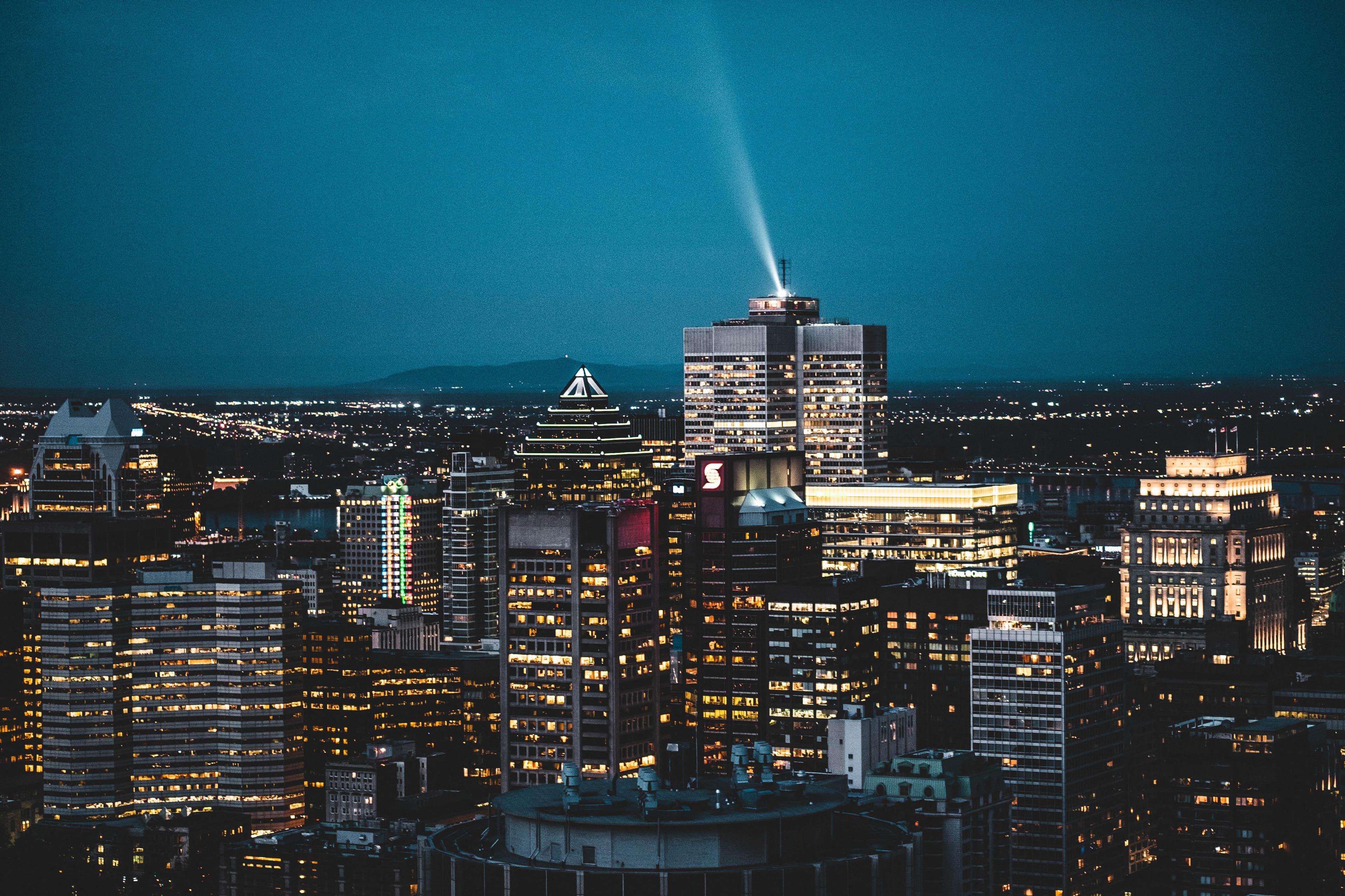 a city view of Montreal at night with dark blue skies and shiny tall gray buildings with yellow lights