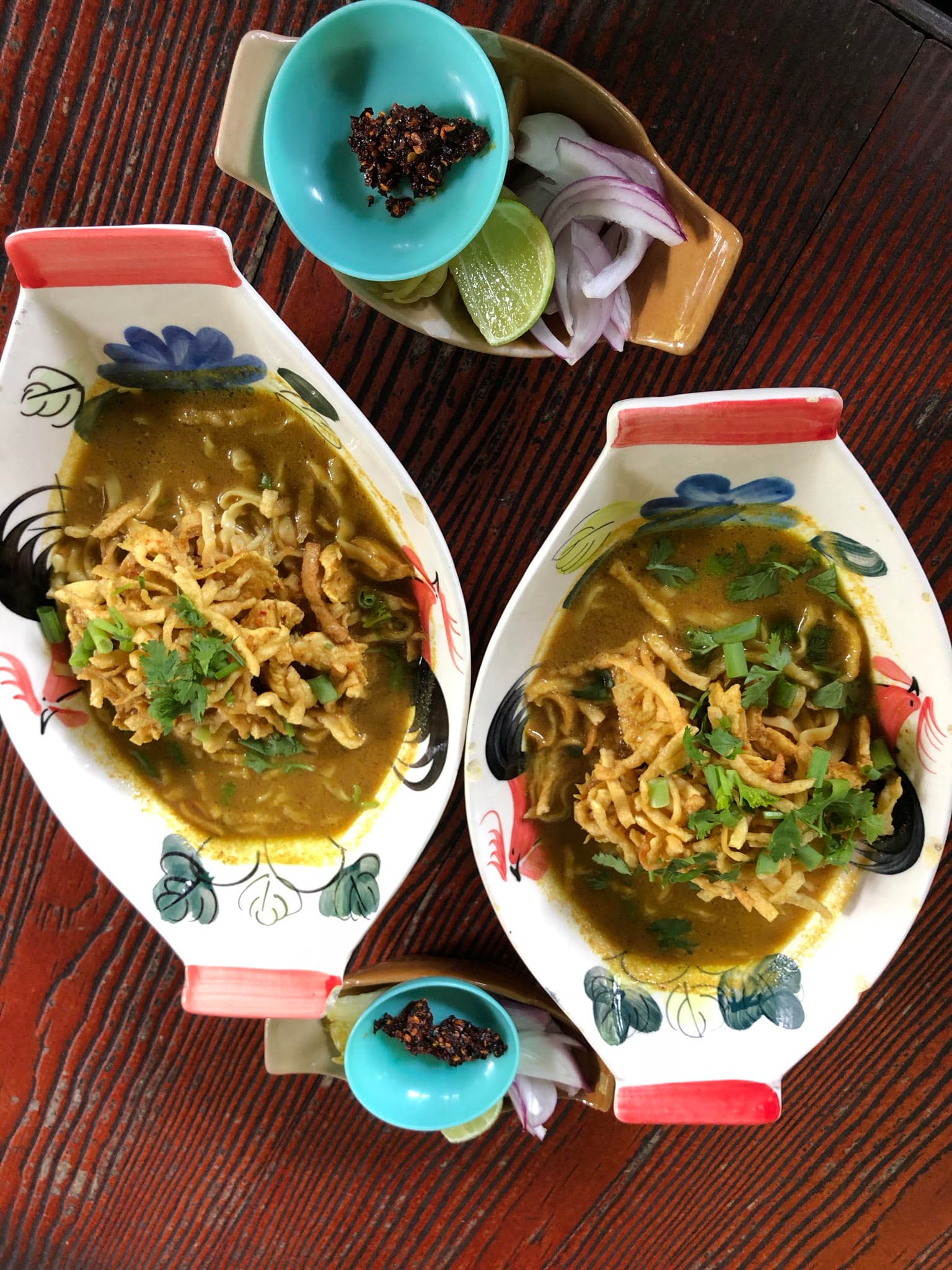 Two oval-shaped dishes full of noodles and garnished with green onions.
