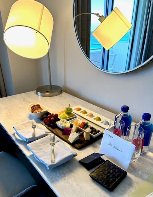 Hotel room welcome card and treats on a table.
