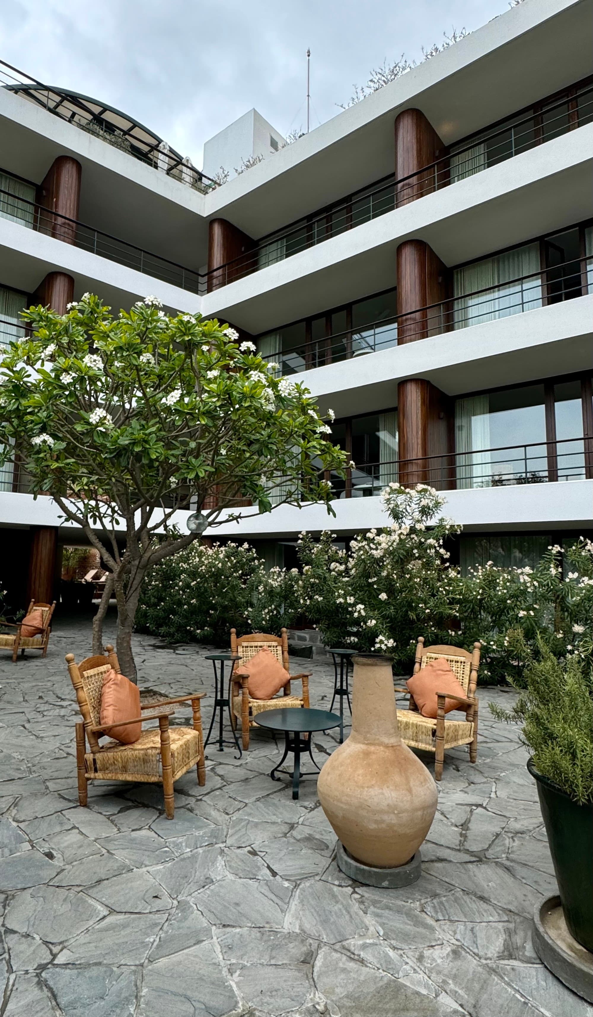 A view of a hotel courtyard with brown Adirondack chairs, tables and plants during the day.