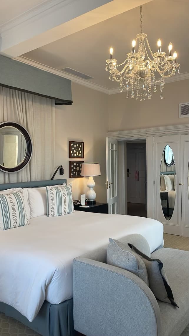 Clean hotel room with white linens and a crystal chandelier.