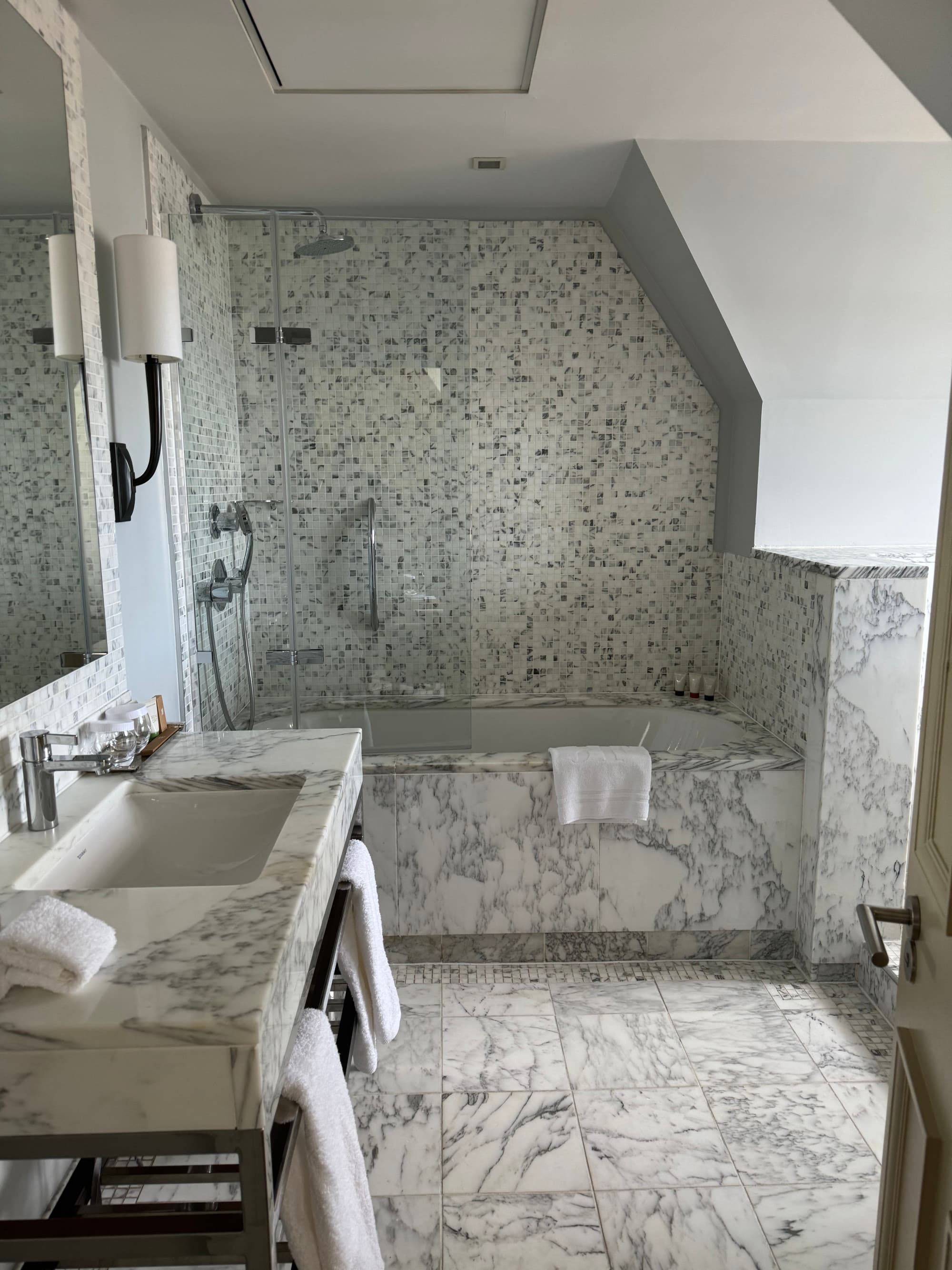 Large grey and white marble bathroom with bathtub and amenities