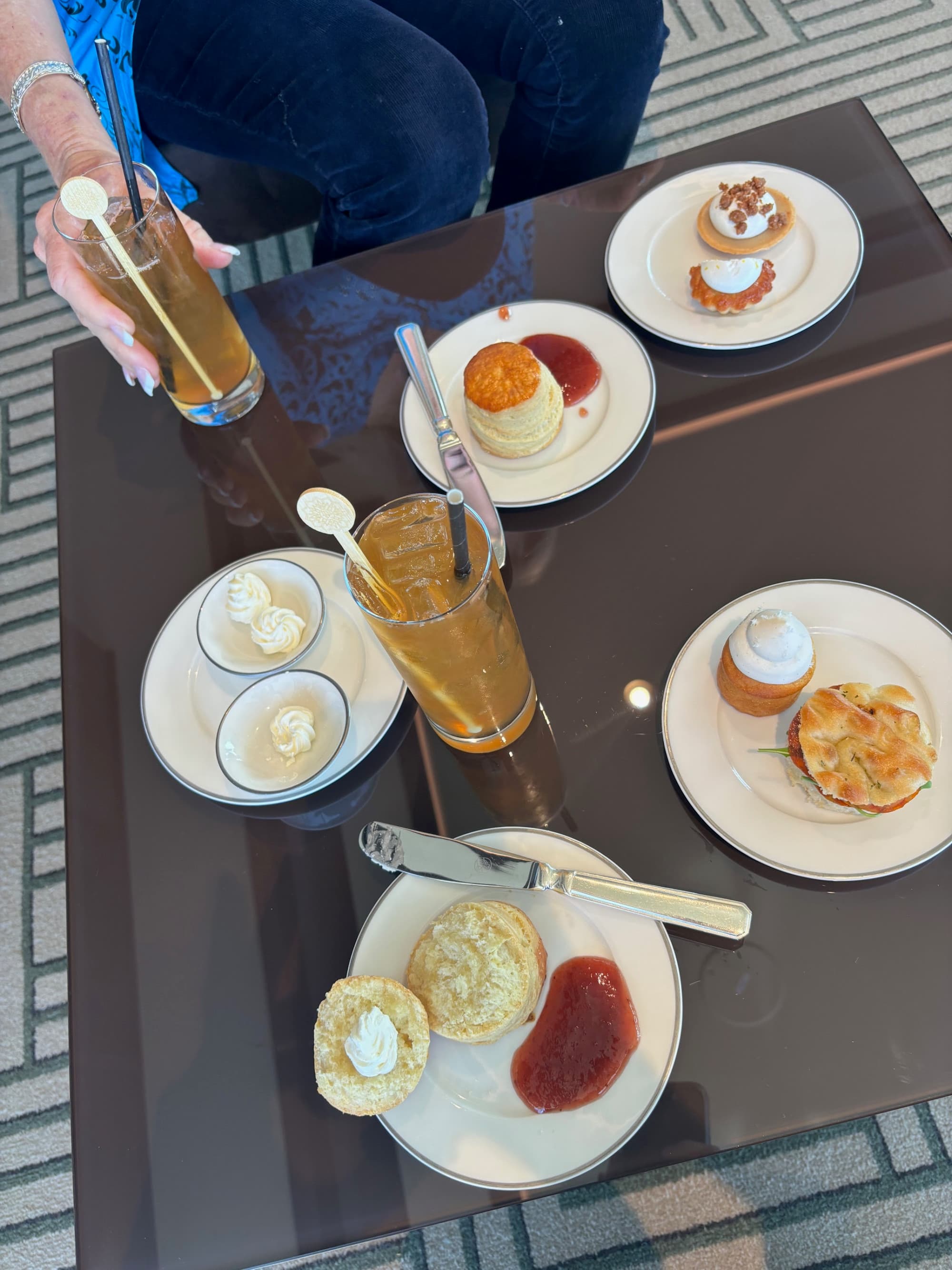 A table set for High Tea with plates of pastries and drinks - Alex Sallis