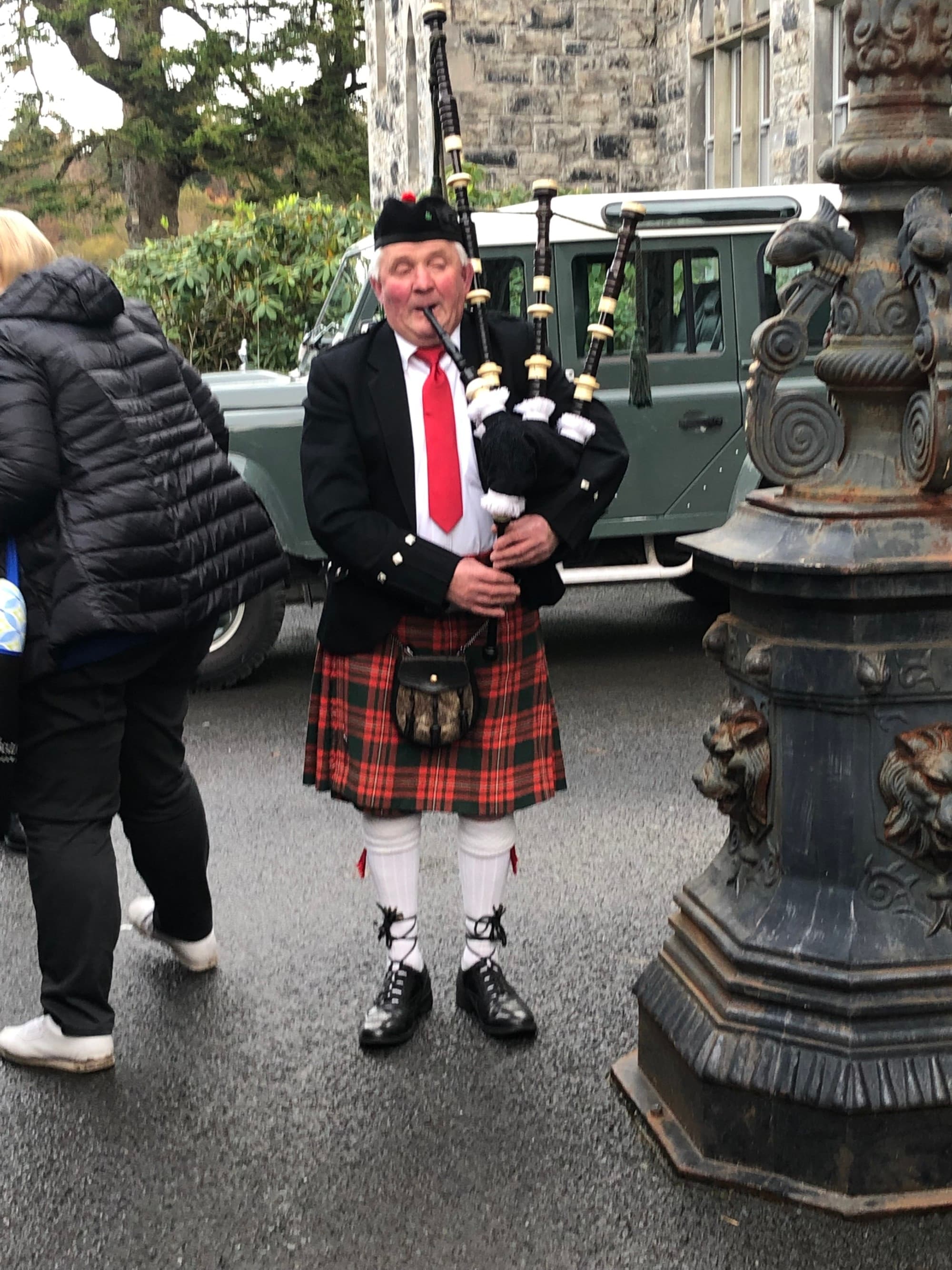A local man in Scotland dressed in traditional kilt playing a bagpipe outside