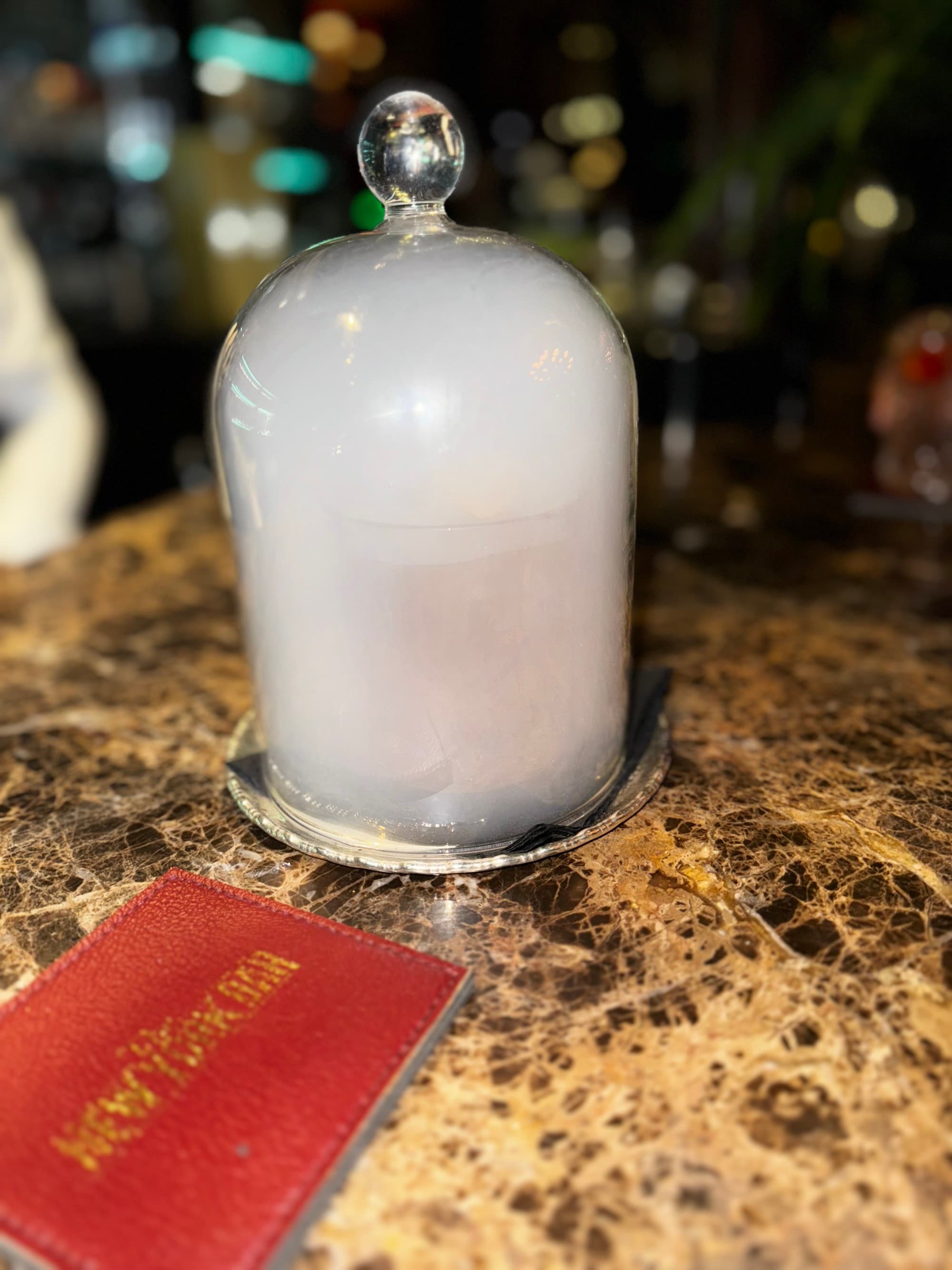 A glass filled with fog on a bar, with a red menu in front of it.