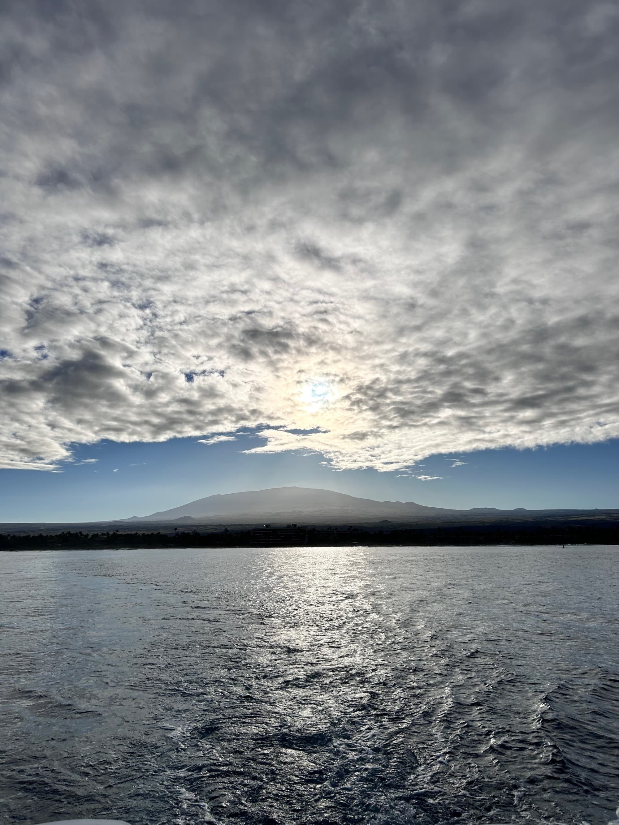 A body of water with a volcano in the distance during the daytime