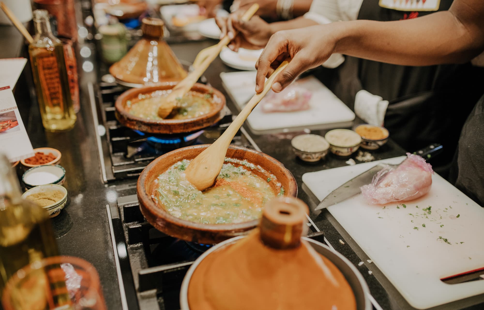 pans containing vegetables and spices sizzle on a stove