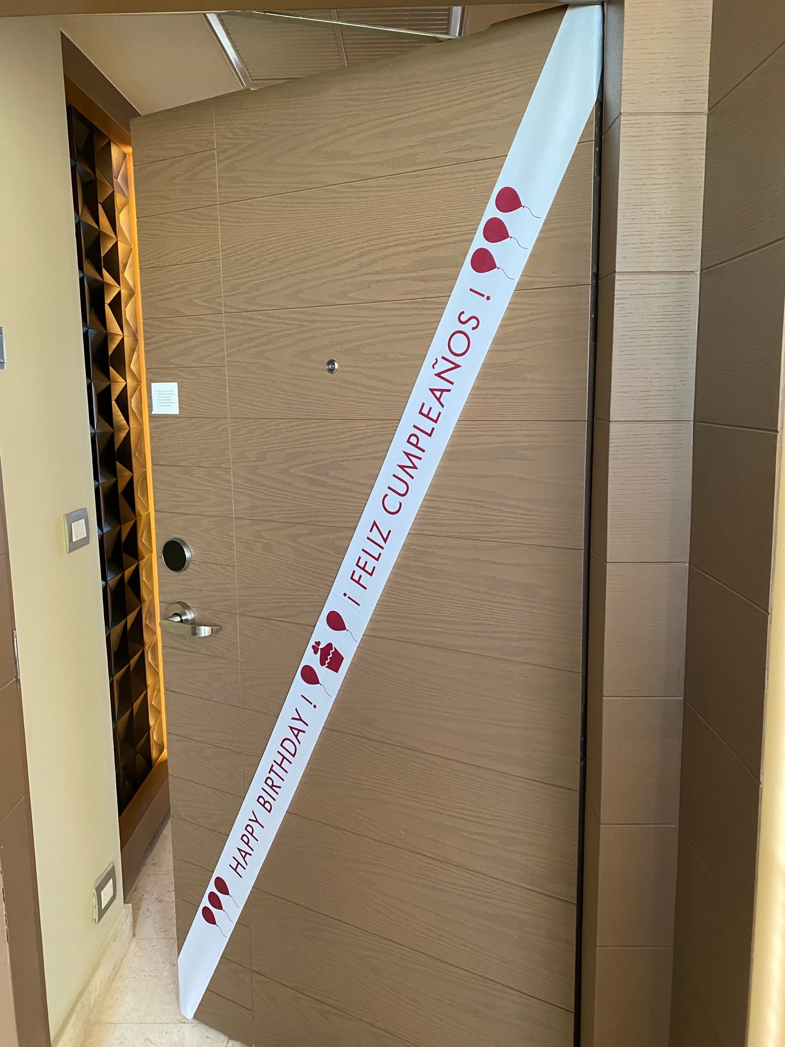 A view of the hotel bedroom door with a sash that read "feliz cumpleaños!".