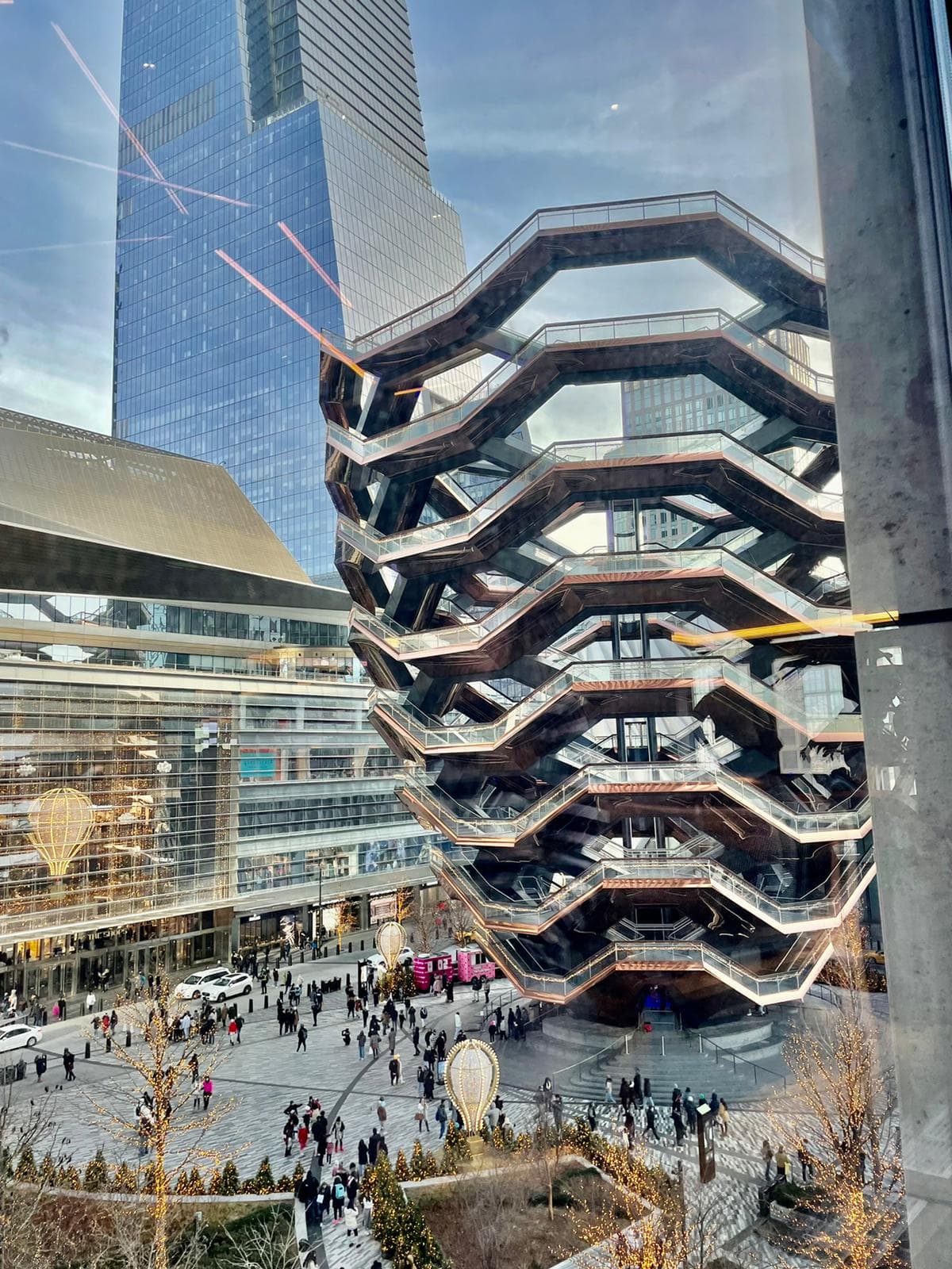 A view of a geometric building exterior with lots of people walking around.
