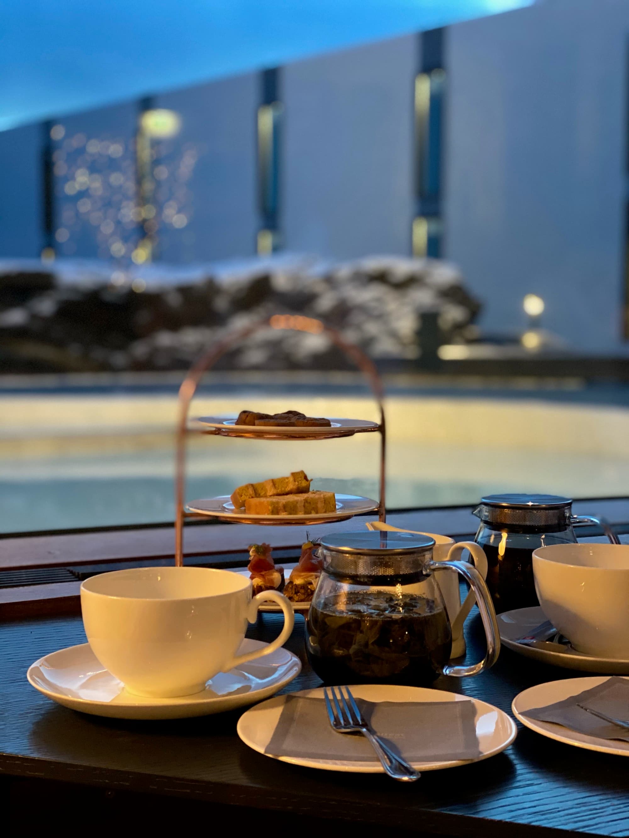 A tiered tray with treats near coffee mugs