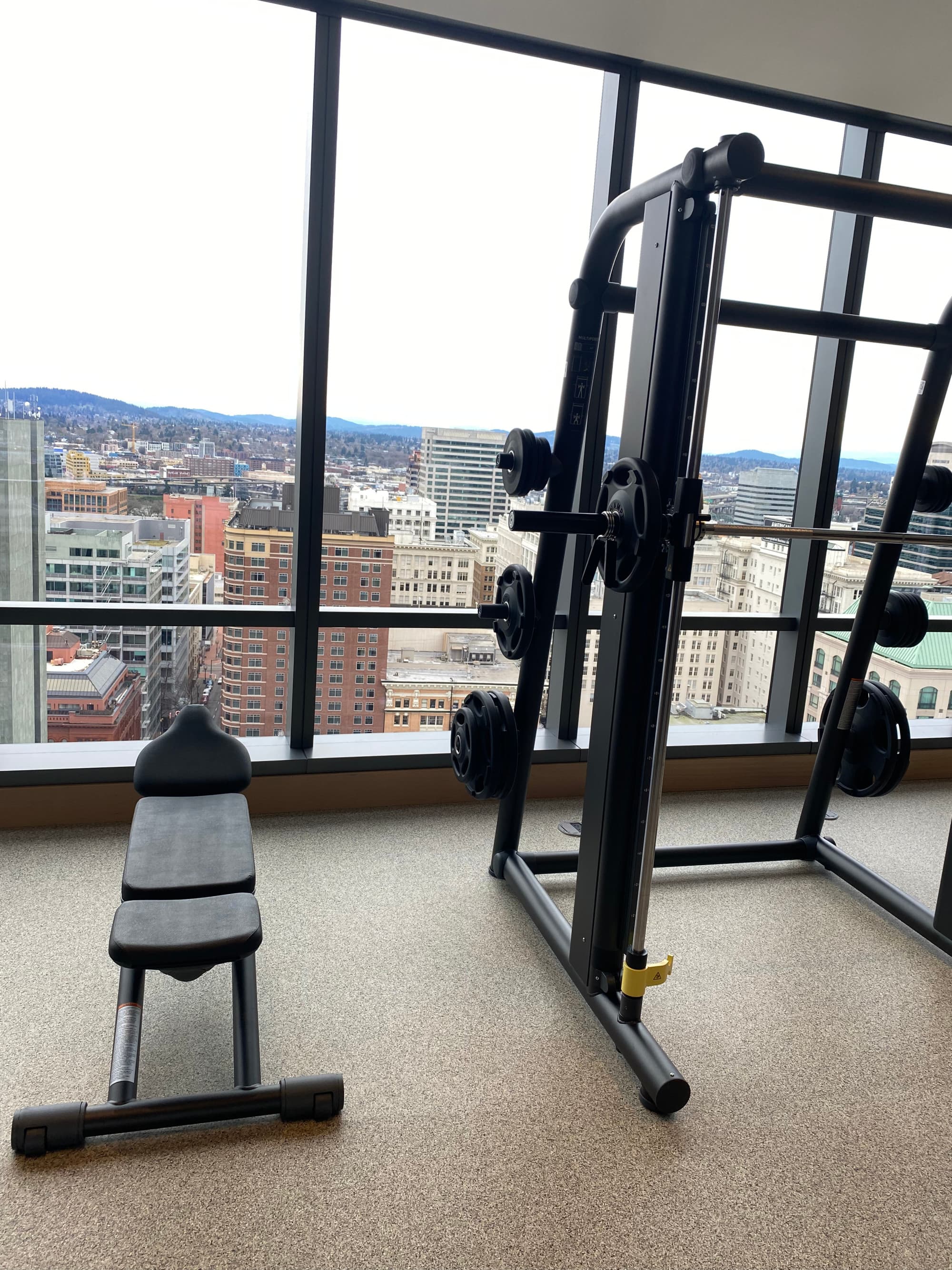 A workout facility with floor to ceiling windows that look out a city view at daytime.
