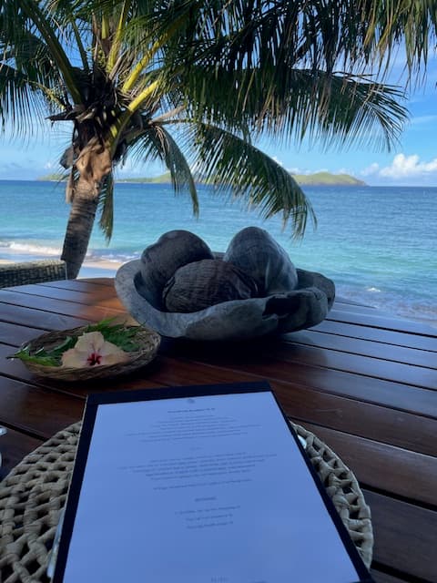 A menu sitting on a wooden table on a beach