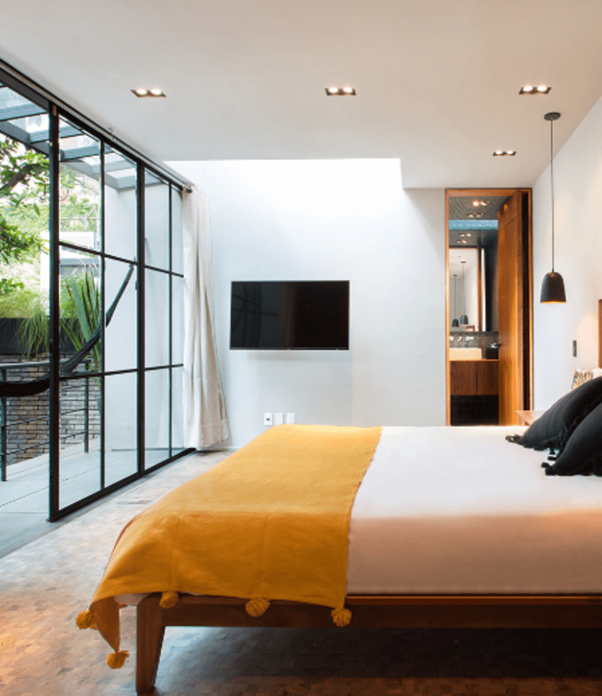 a bed with a yellow blanket overlooks a sleek patio
