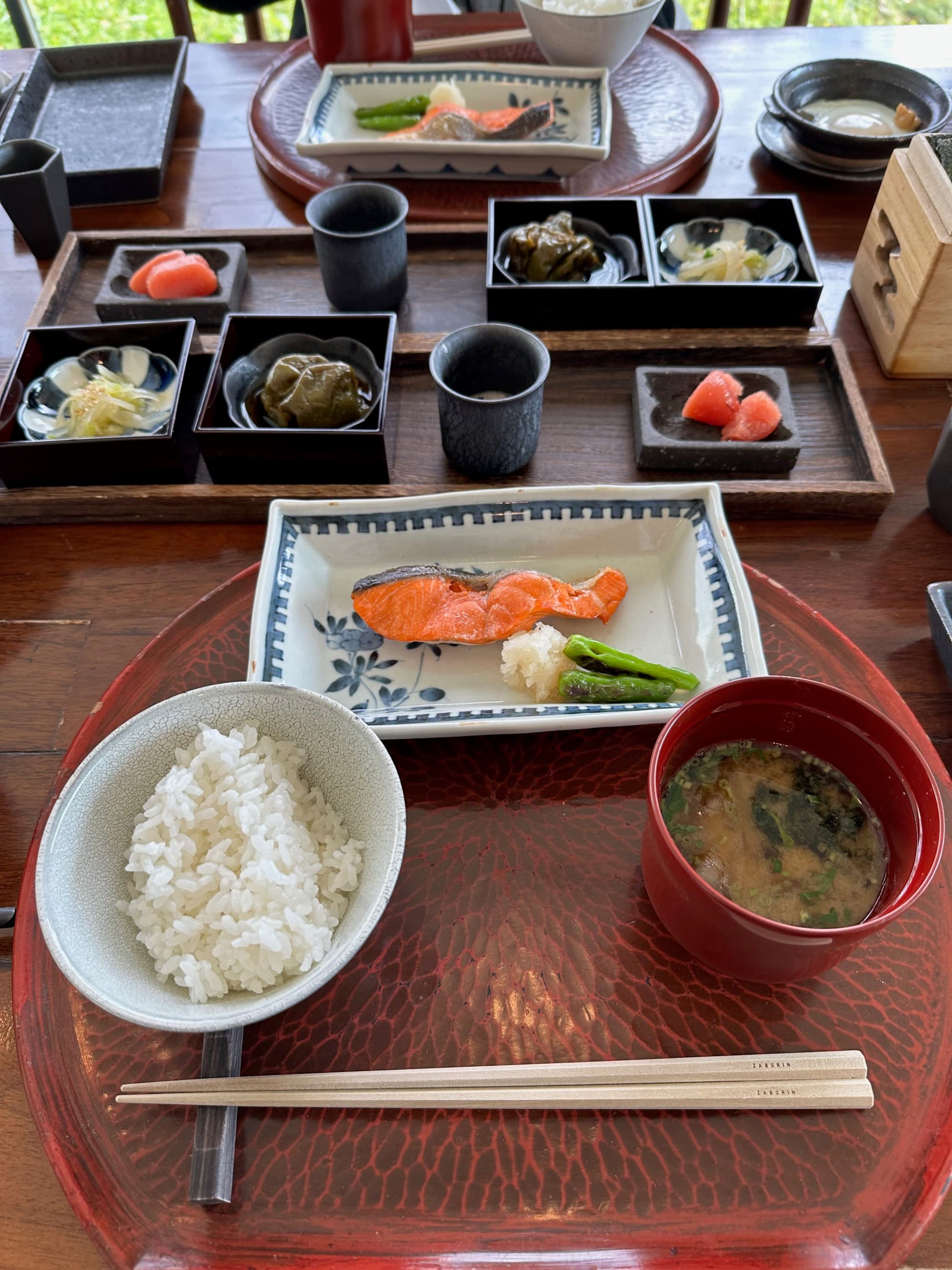 Plates of Japanese breakfast food like rice and miso soup on a table at Zaborin.