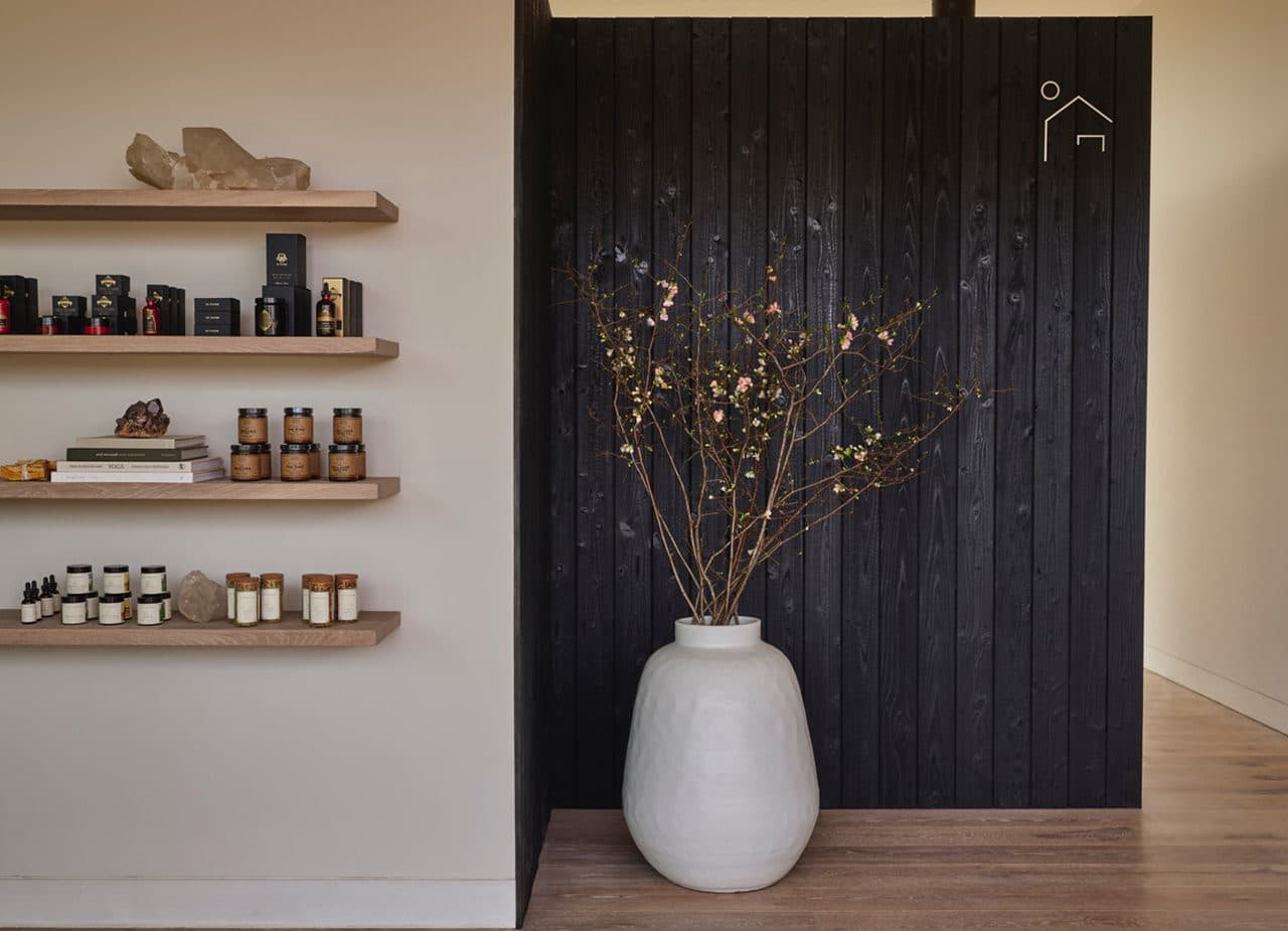 a black pot filled with branches sits on a wooden floor