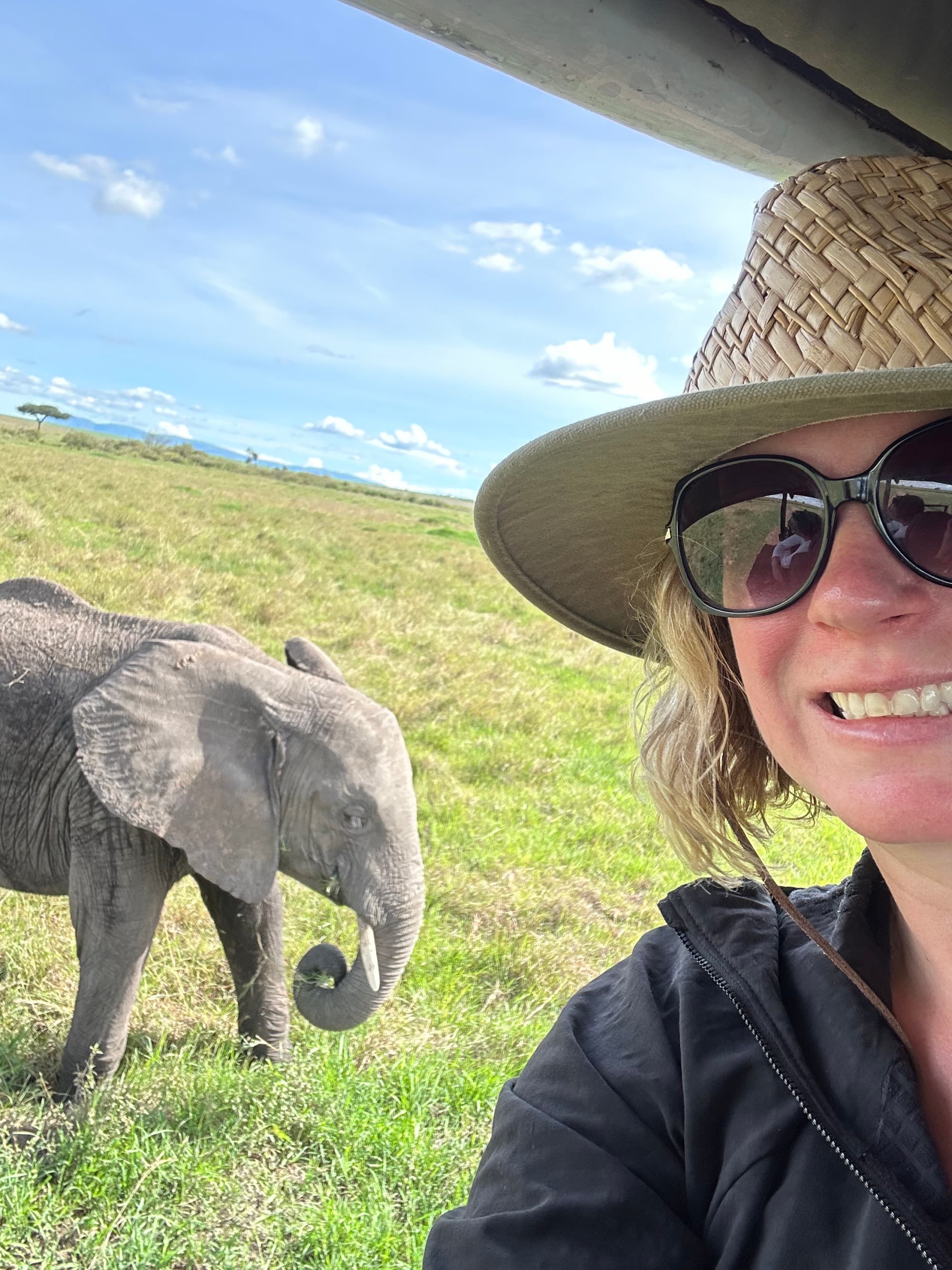 Travel advisor posing with an elephant in the back.