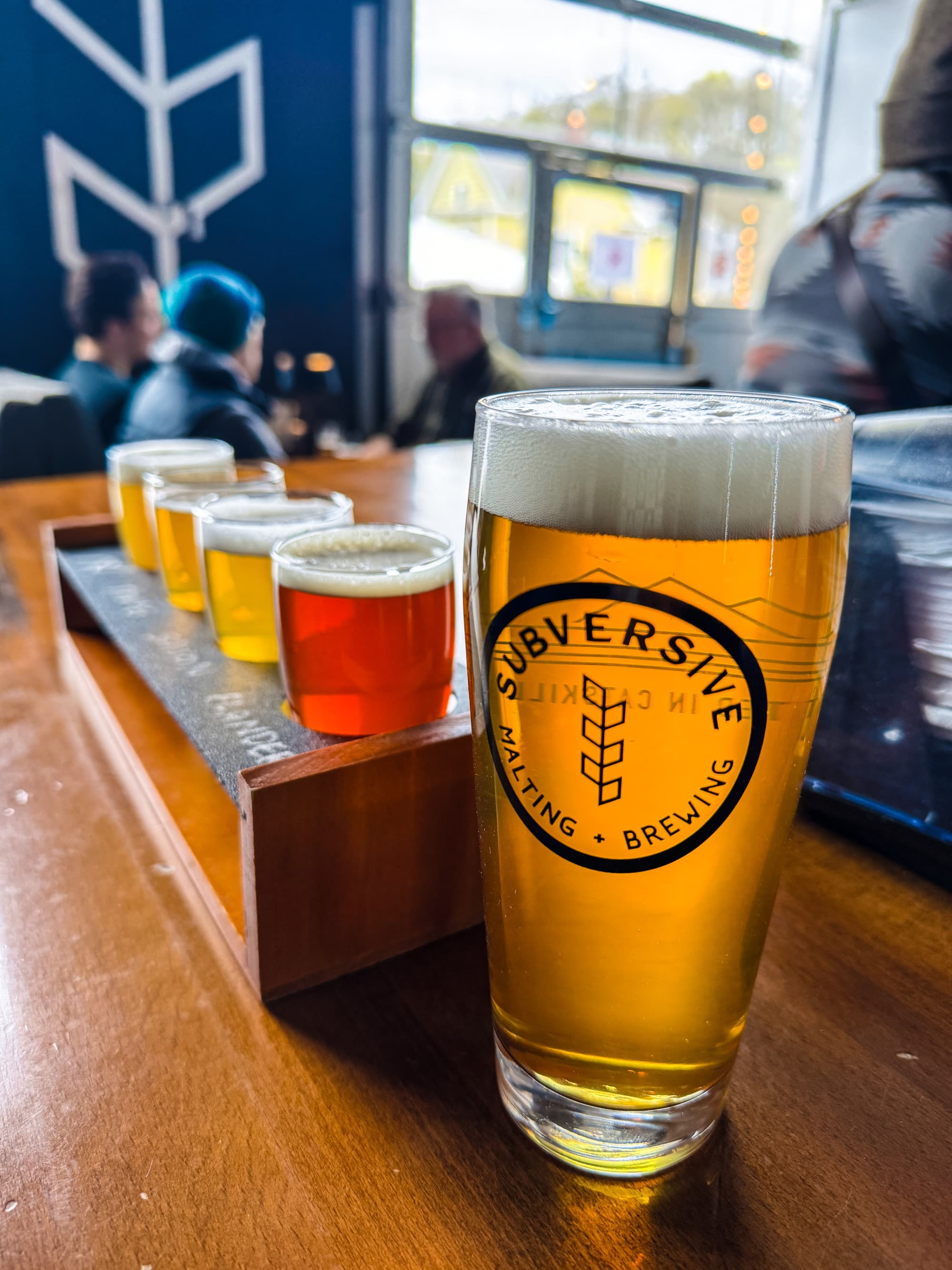 A close-up view of a draft beer in a glass, with other samples of beer lined up behind it at Subversive Brewing Beer.