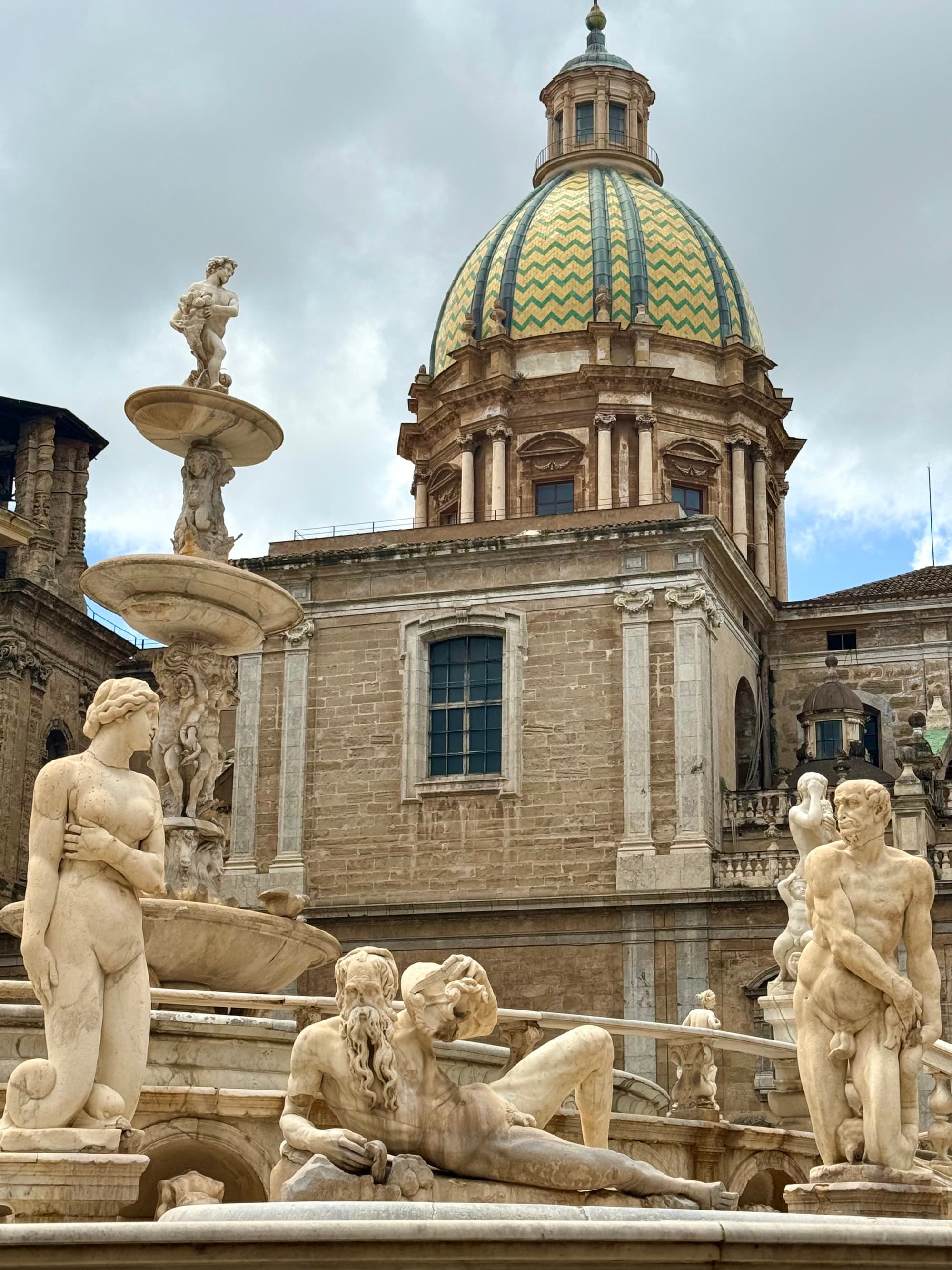 City architecture in Siciliy with a dome-shaped building and multiple statues