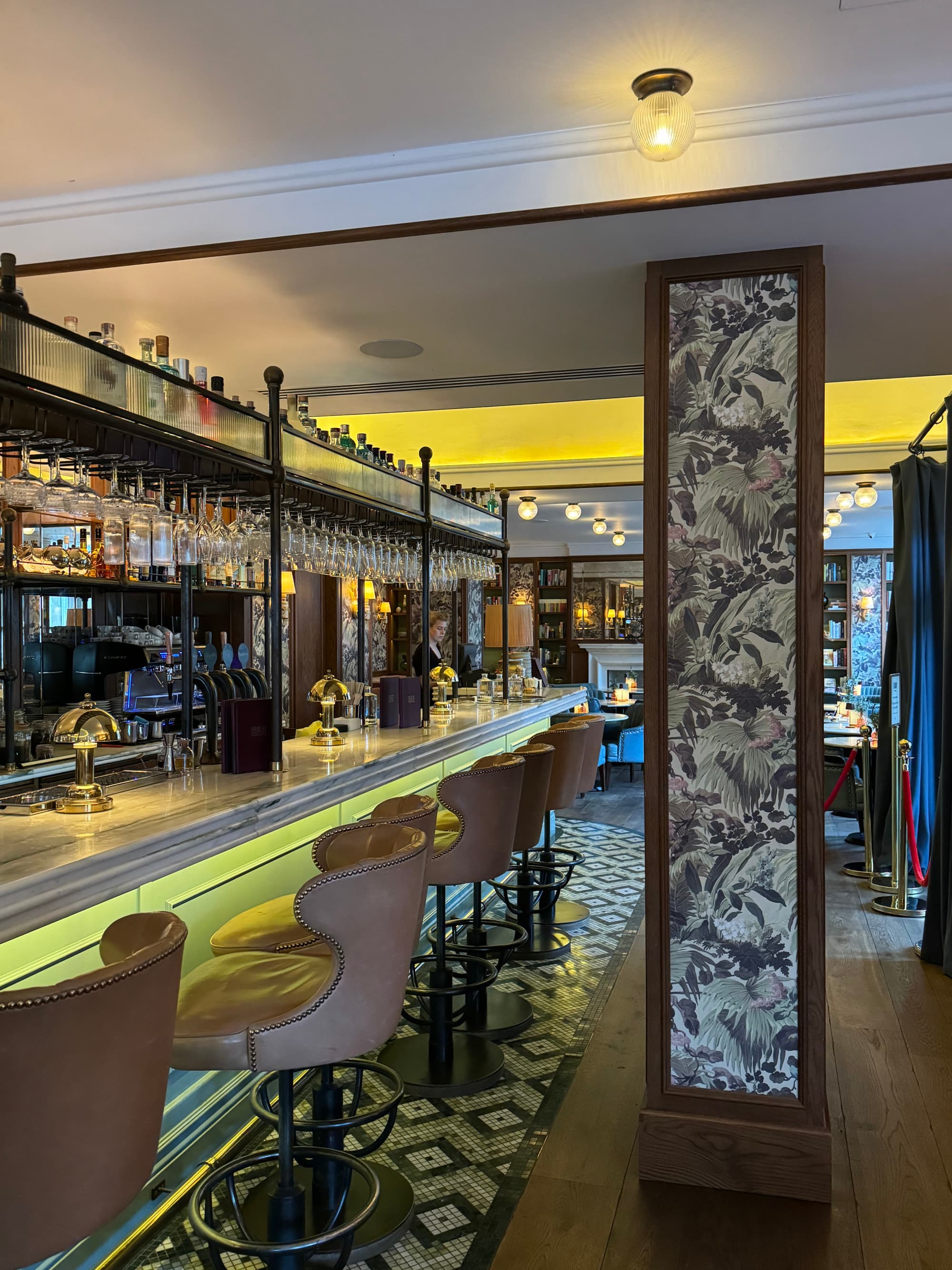 View of the inviting bar at the Balmoral featuring high cushioned chairs and a mirrored bar back
