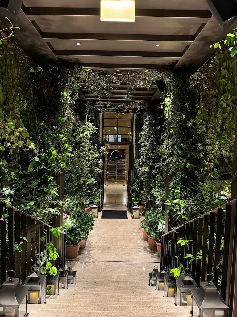 The entrance to the Rome EDITION hotel, with greenery on either side of a descending staircase.