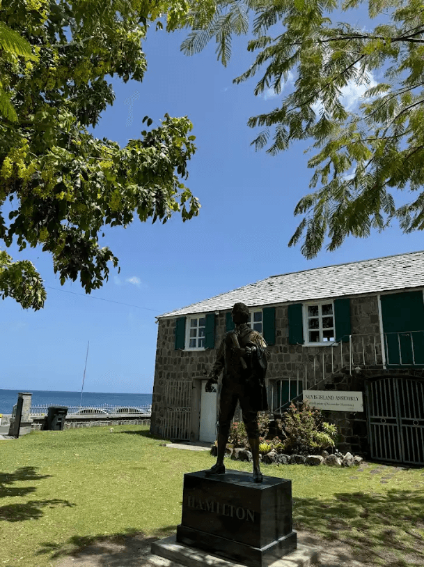 A green lawn surrounding a historic building on the oceanside with blue skies above during a stop on the Alexander Hamilton Island Tour.