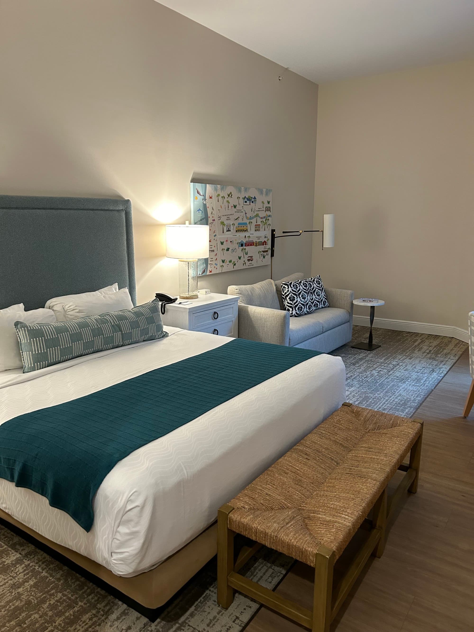 Guest room with a large bed made with white linens and a blue throw blanket.