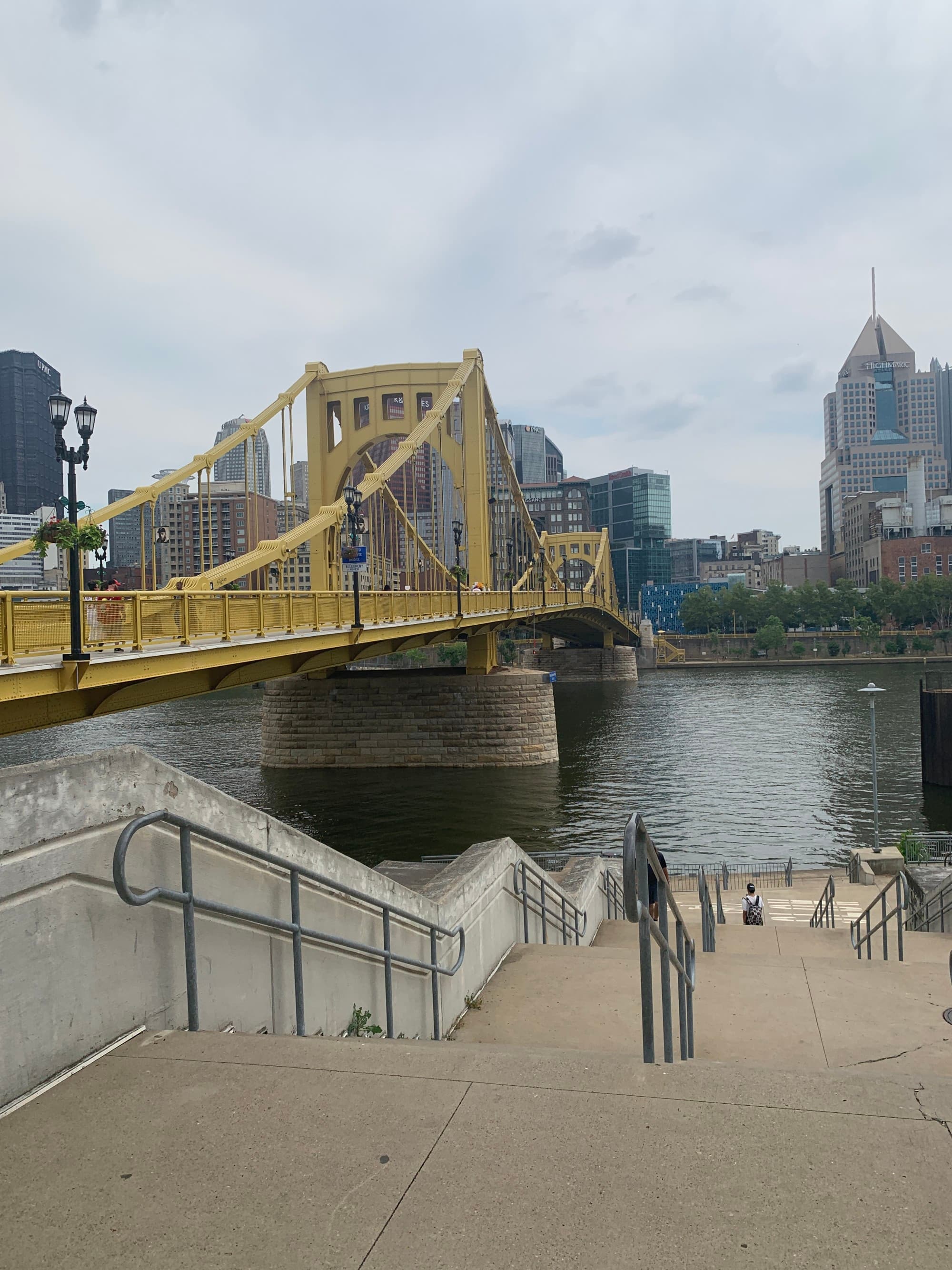 Yellow bridge over a canal of water with stairs in the foreground.