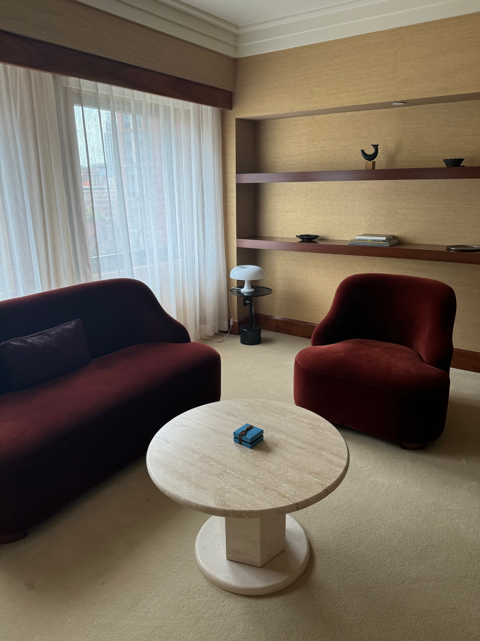 Sitting area with a chic interior and a large window with drapes.