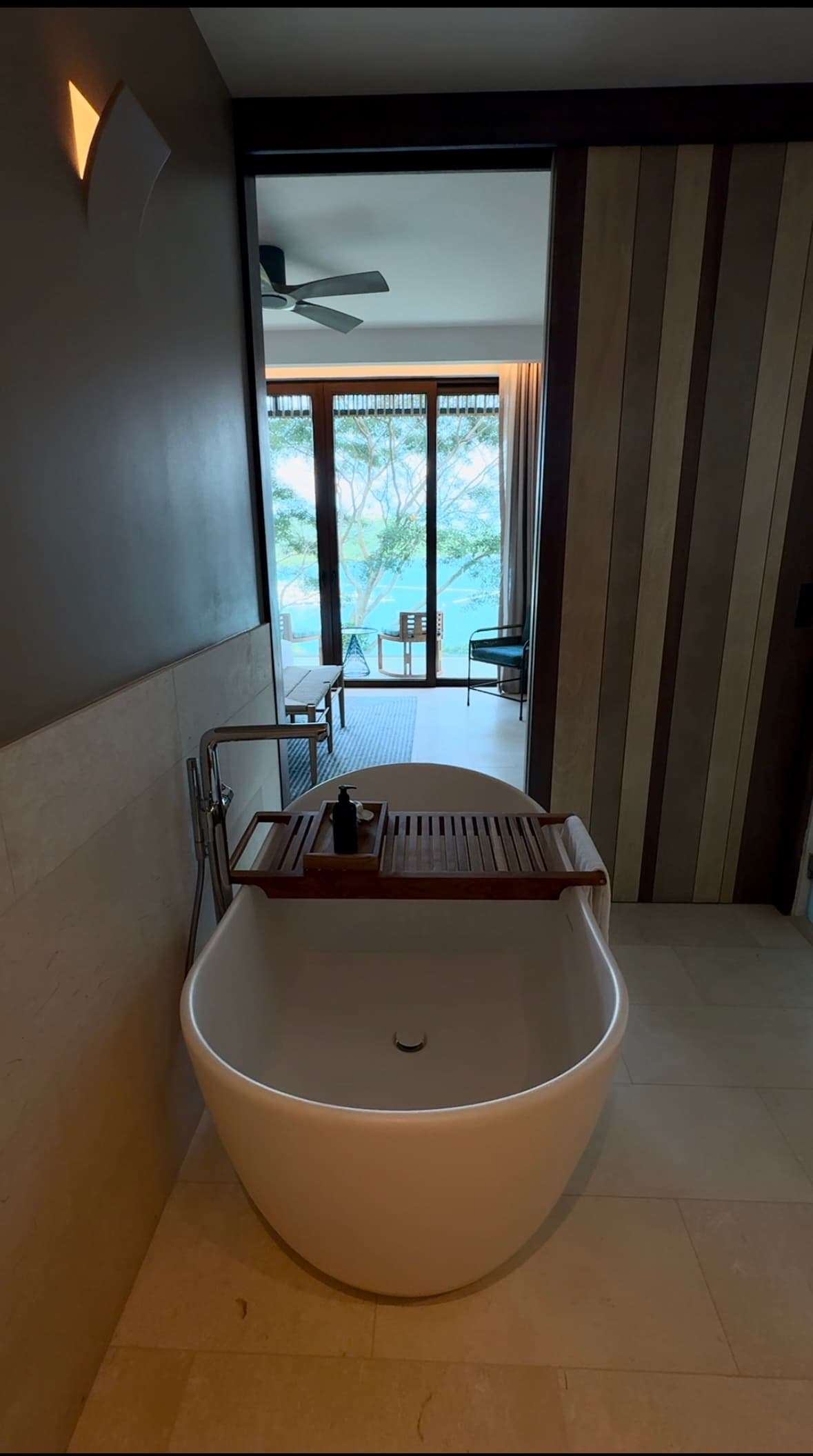 The Andaz villa bathroom has a large bath with wide windows as the sun filters in on a sunny day.