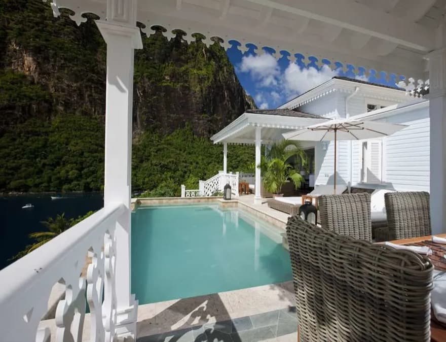 porch with white railing looking at a small pool with green mountain in the background