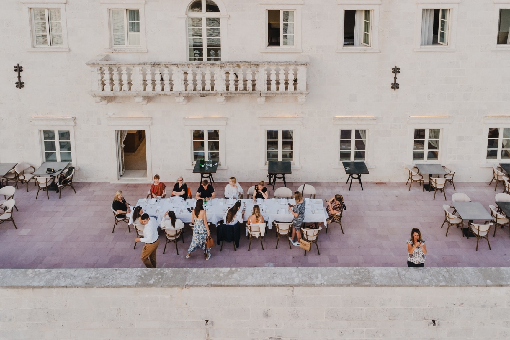 people sit at a sidewalk table in front of a white building