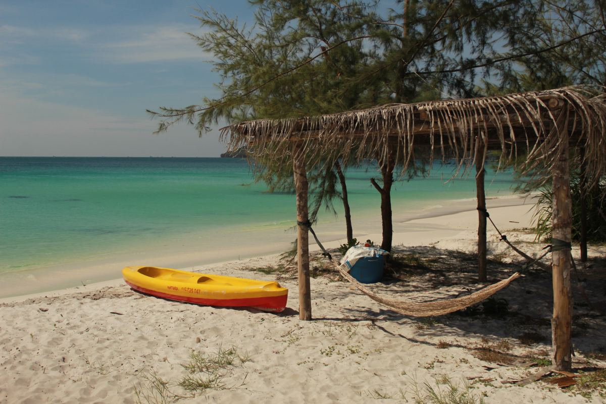 Yellow canoe on a beach near a hammock