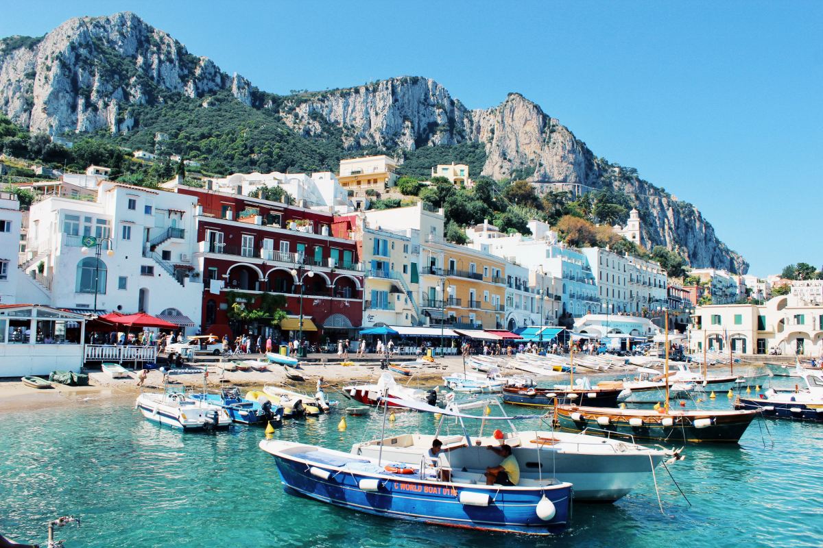 a colorful cliffside town with a bustling harbor