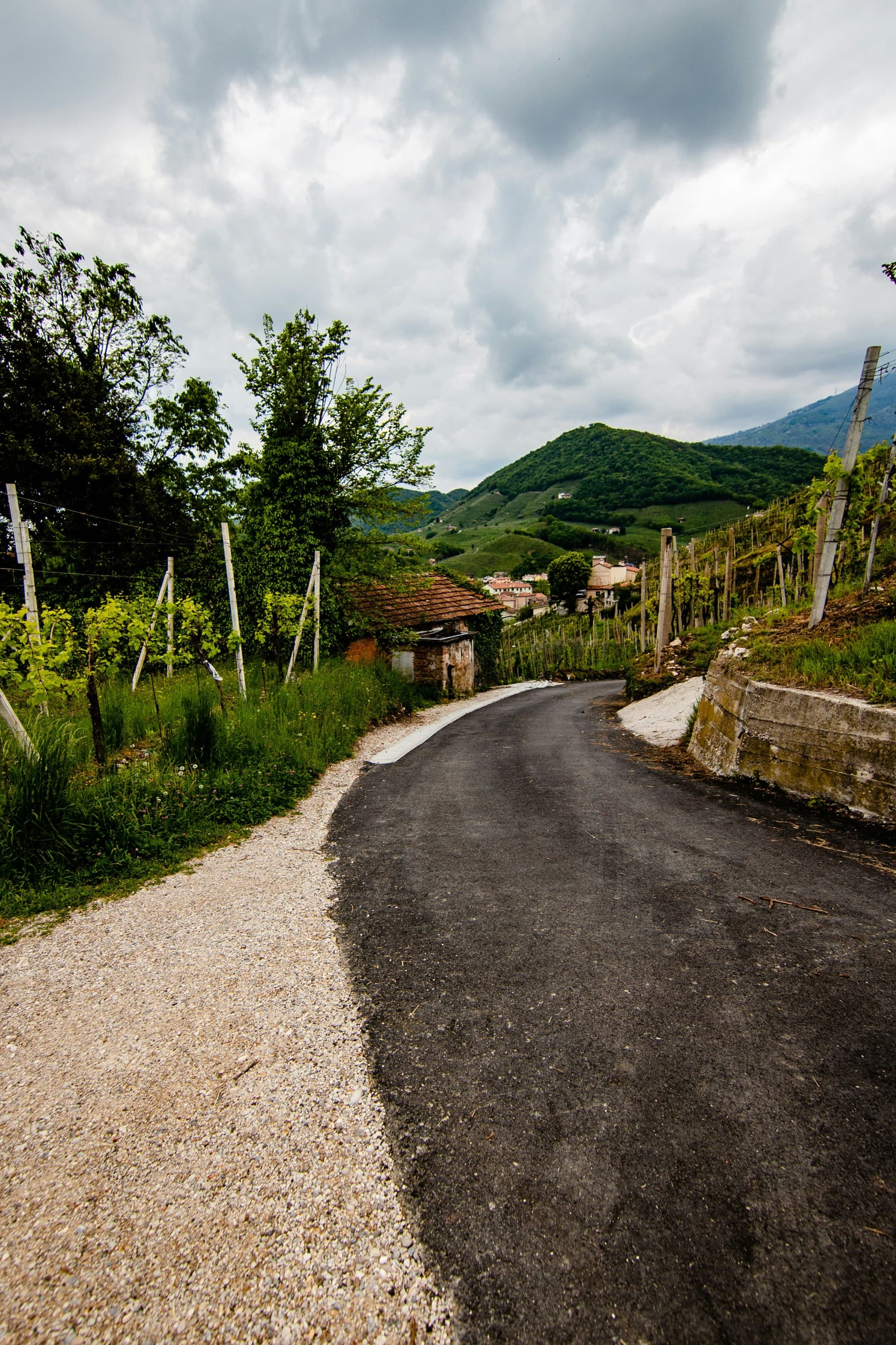 gray-concrete-road-between-green-grass-field-under-white-cloudy-sky