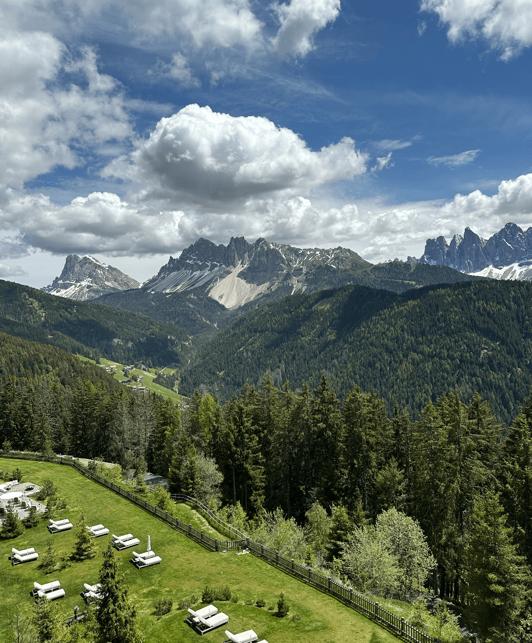 View of the lush valley and mountains on a sunny day dotted with clouds.