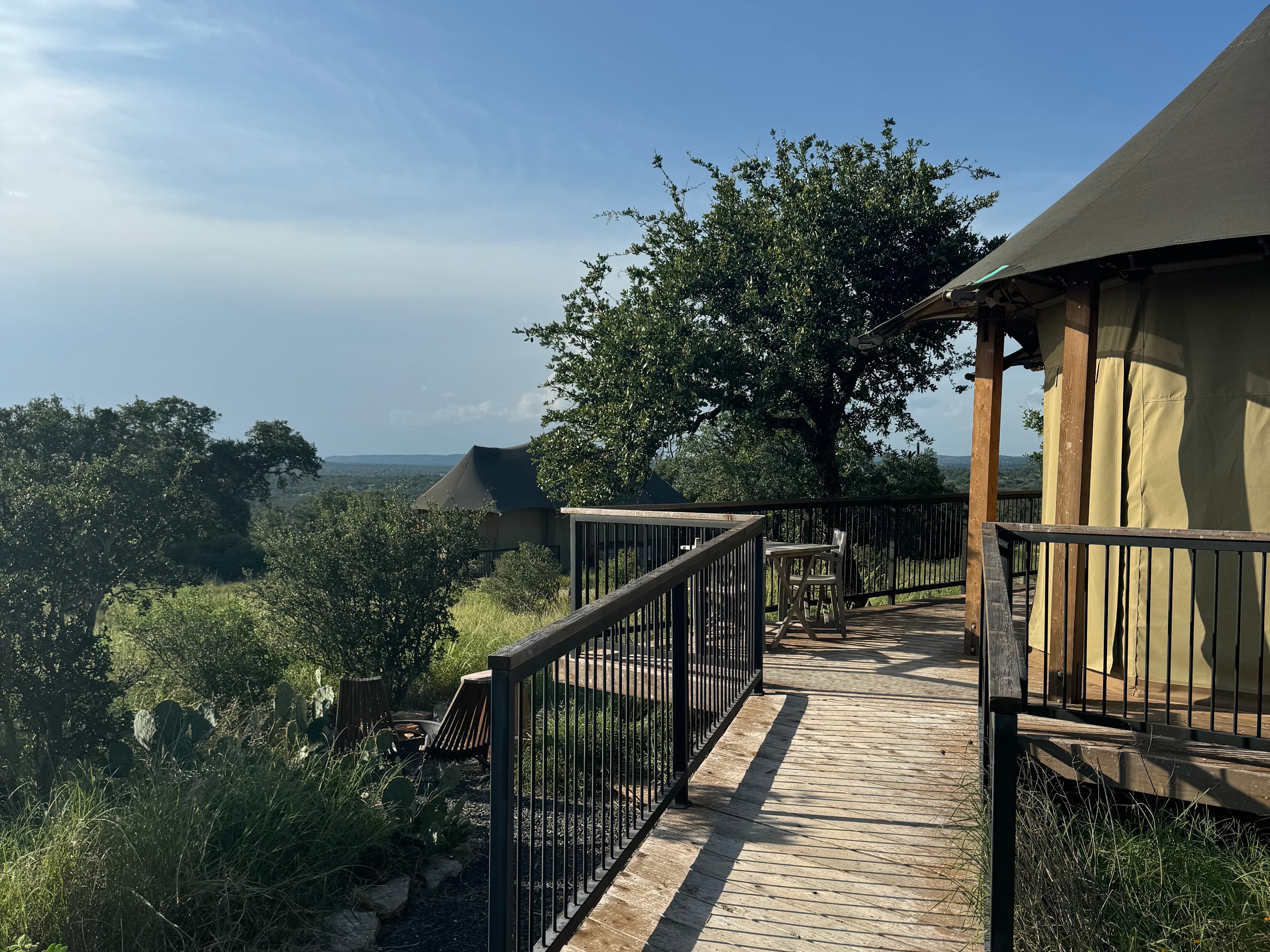 The outside of a tent with a terrace overlooking trees