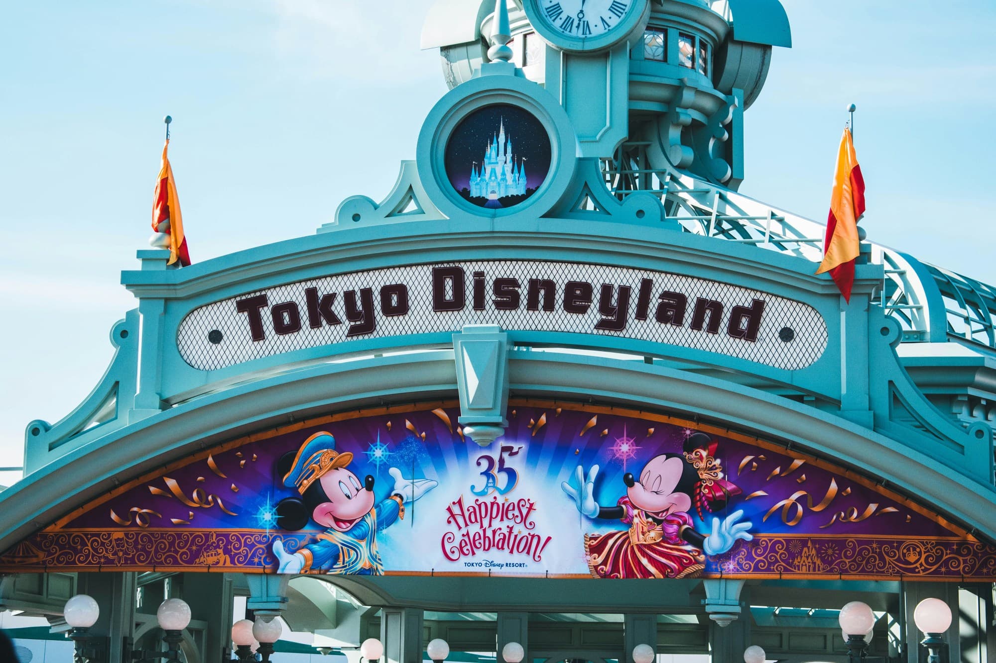 An image of a large Tokyo Disneyland sign on blue exterior with image of Mickey and Minnie Mouse below.