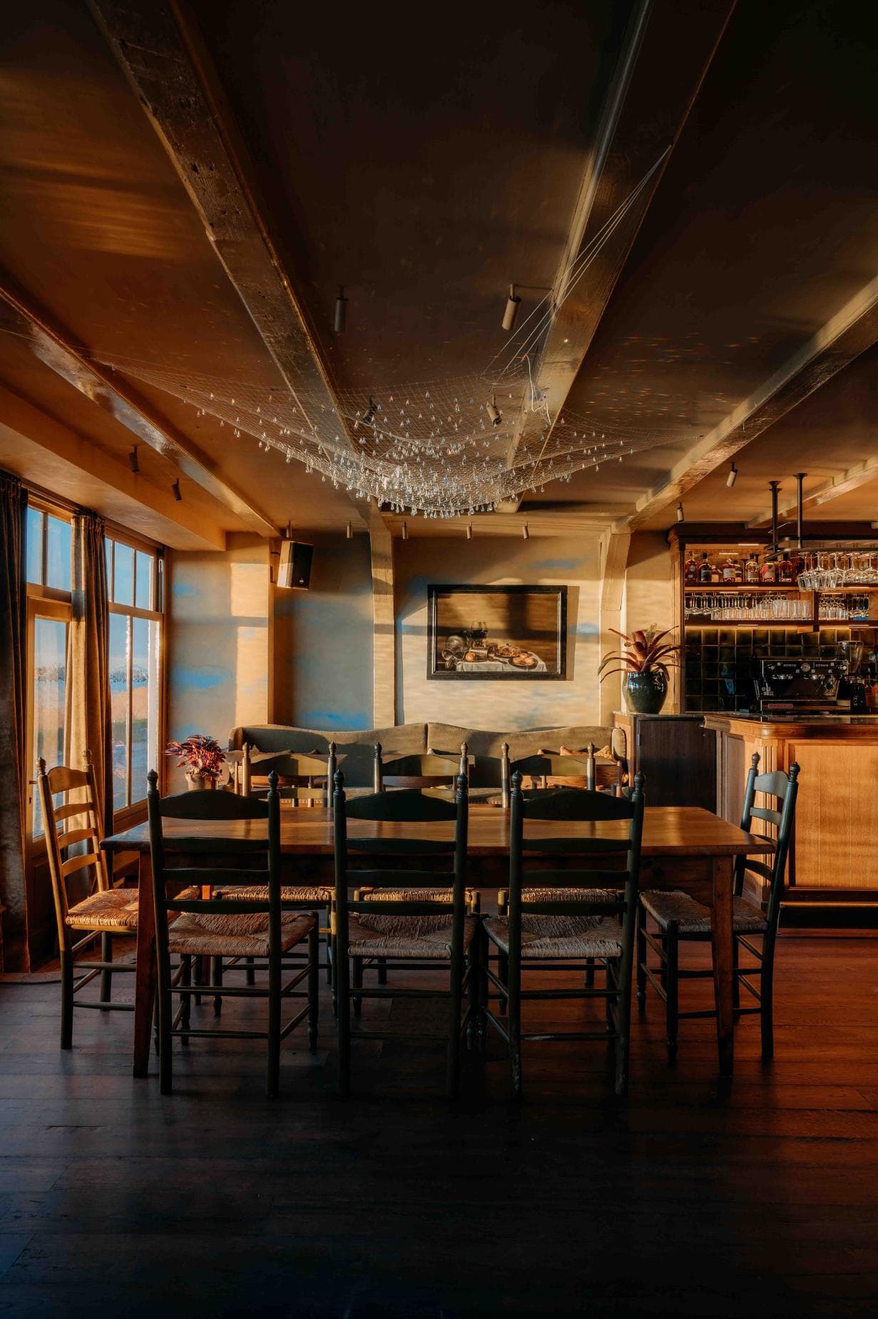 A cozy wood dining room with floor-to-ceiling windows at sunrise.