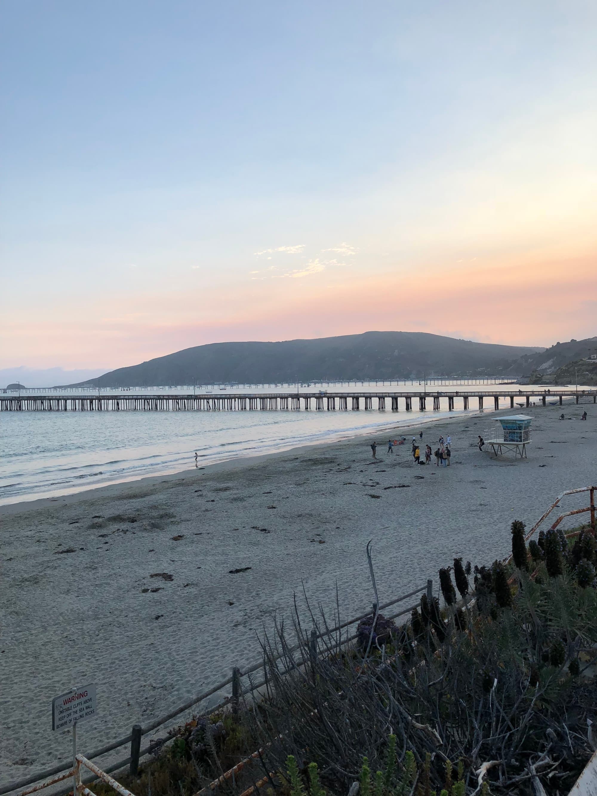 A beach and water during a sunrise with a hill in the distance