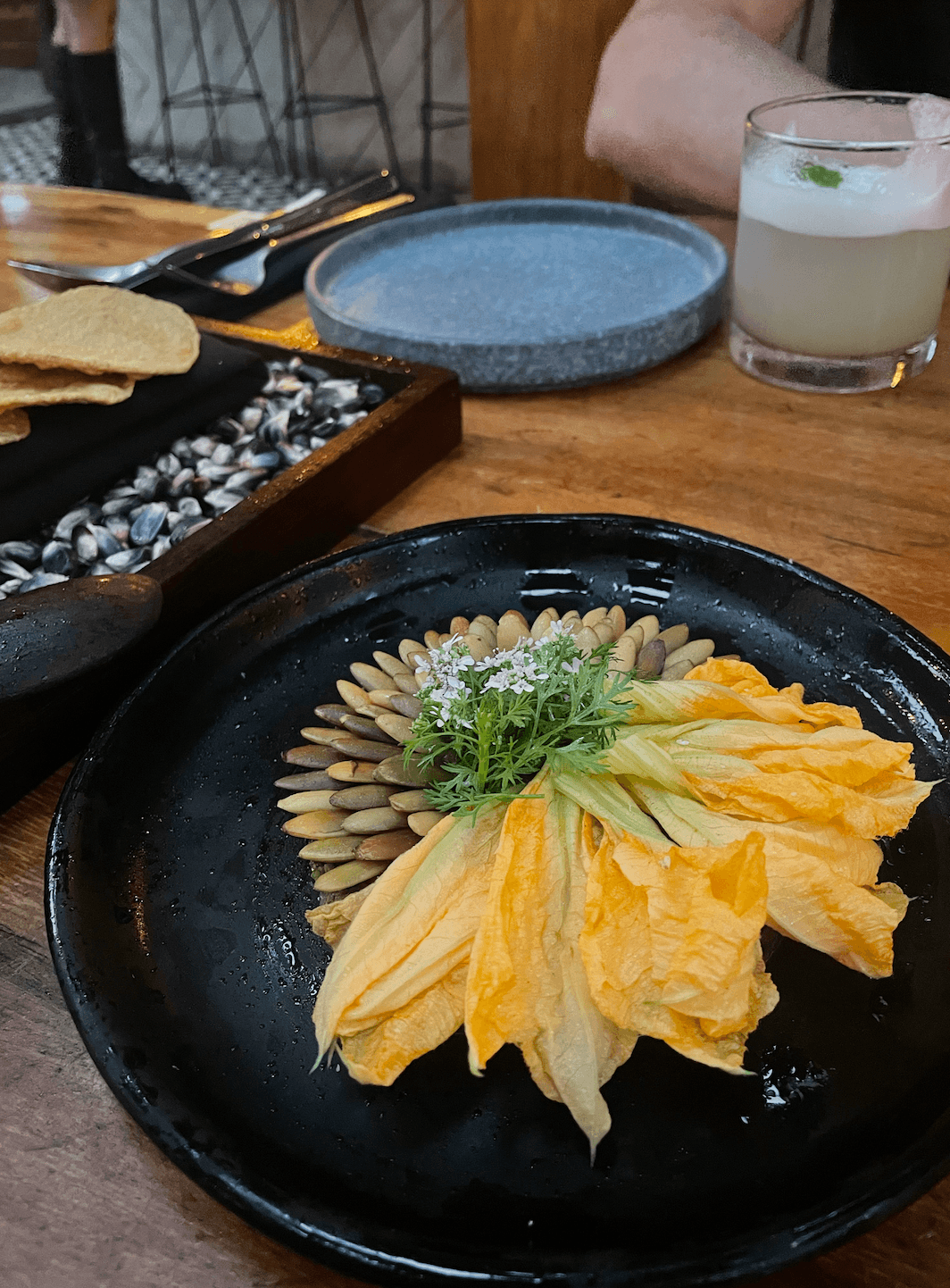 A plate of yellow food with pepitas and additional dishes in the background.