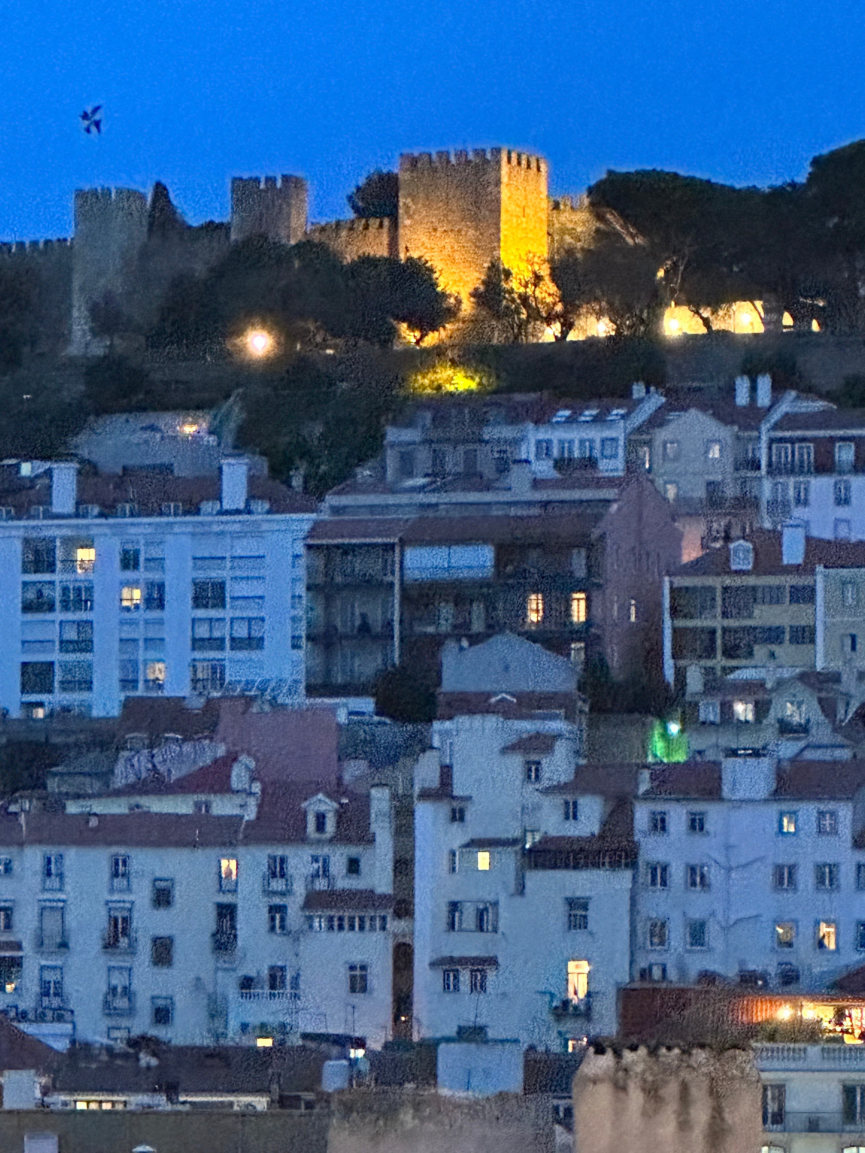 Night view of a city with buildings on a hillside and illuminated castle