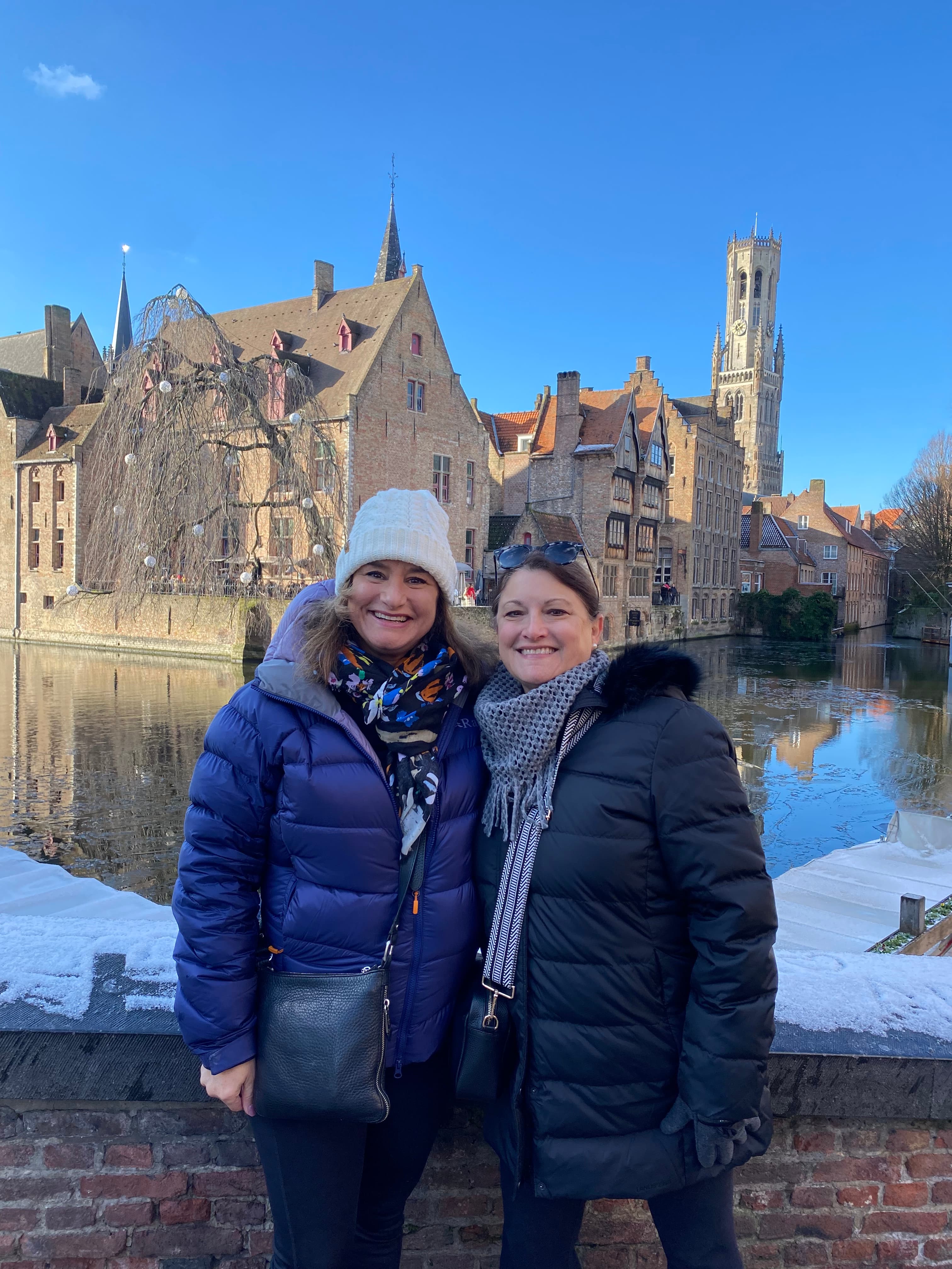 Travel advisor Leslie posing with a friend wearing a blue jacket and hat in front of a river